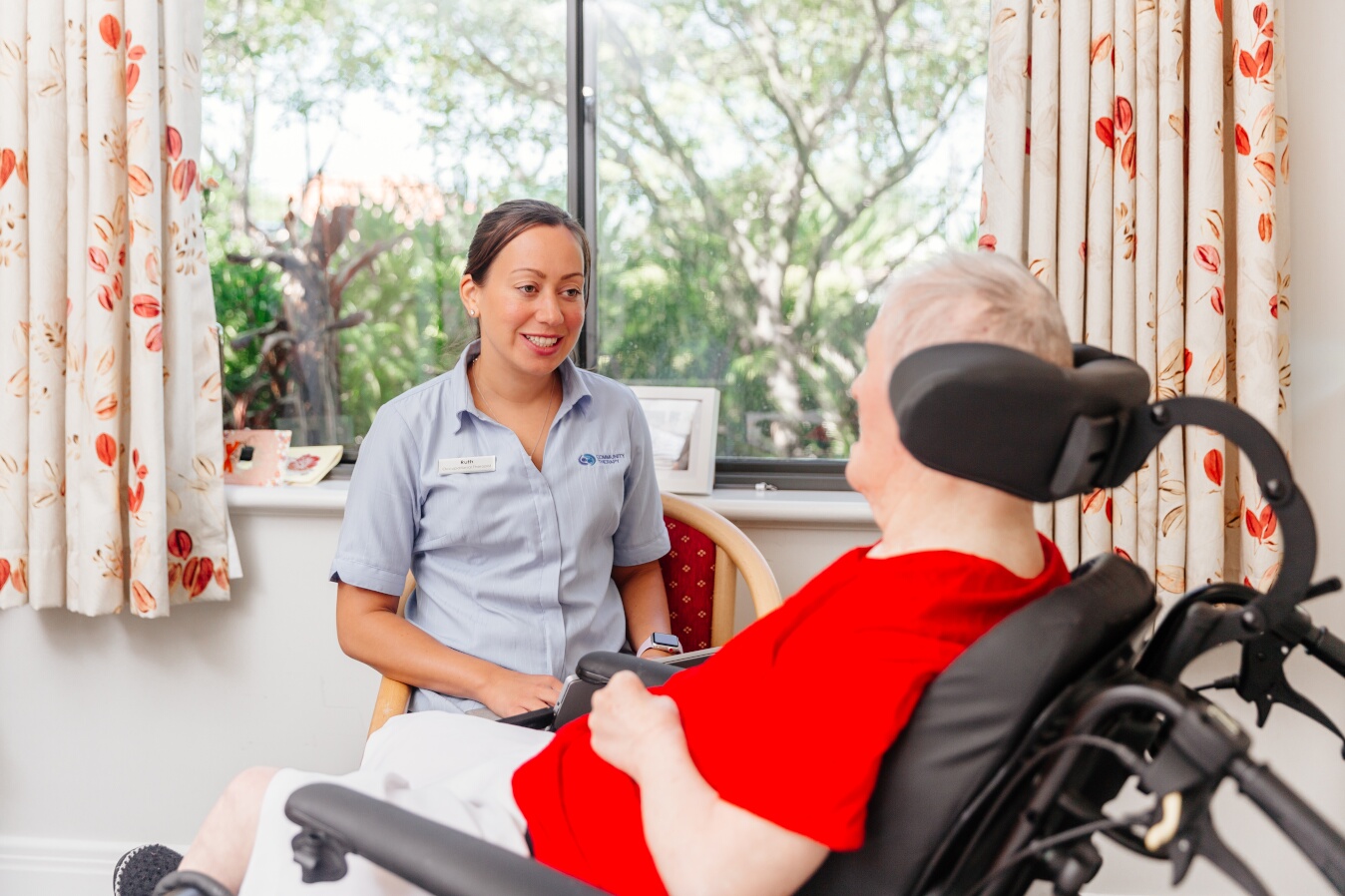 Community Therapy physiotherapist talking to one of our clients in a wheelchair
