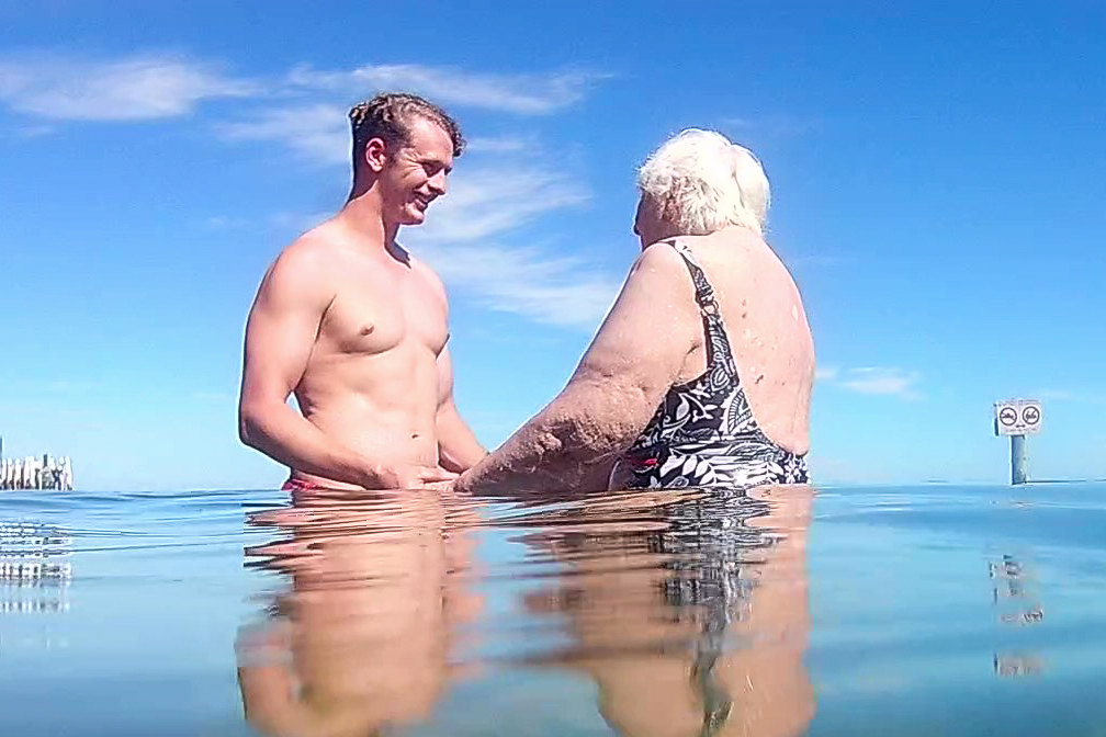 Physiotherapist supporting a client during a hydrotherapy session at the beach