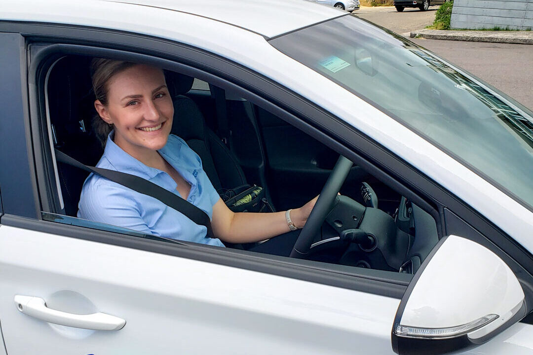 Occupational Therapist smiling from the drivers seat in a car