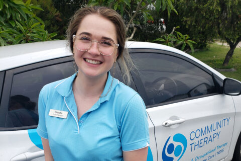 Portrait image of a physiotherapist in front of a Community Therapy branded car