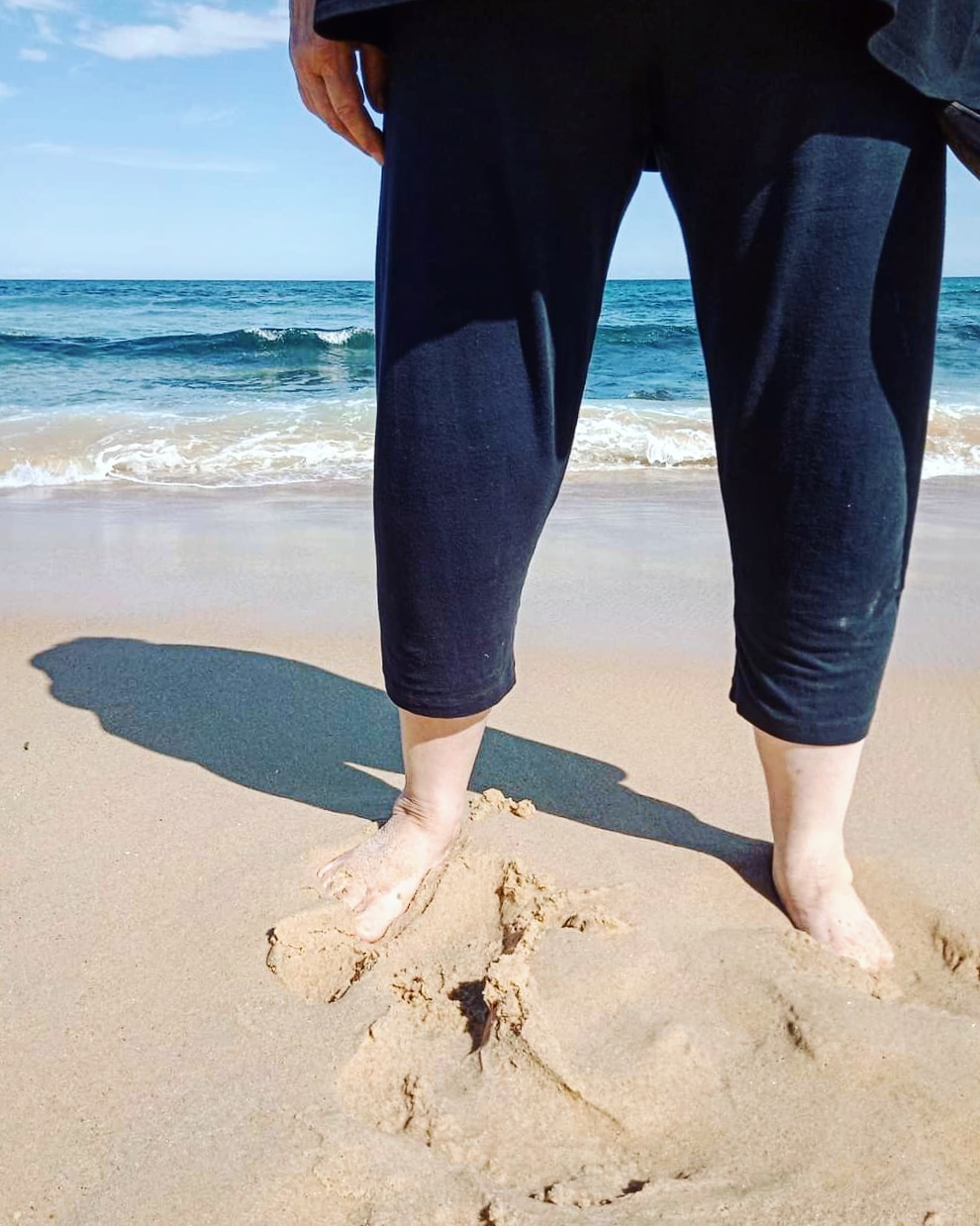 Image of a client's legs walking barefoot on the beach