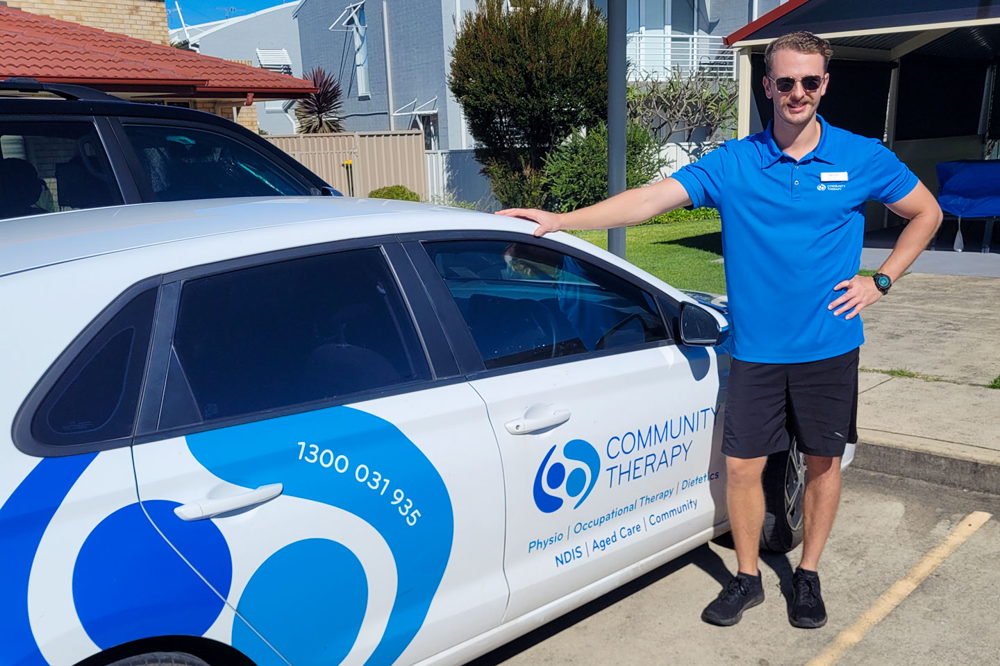 Physiotherapist standing by Community Therapy branded car