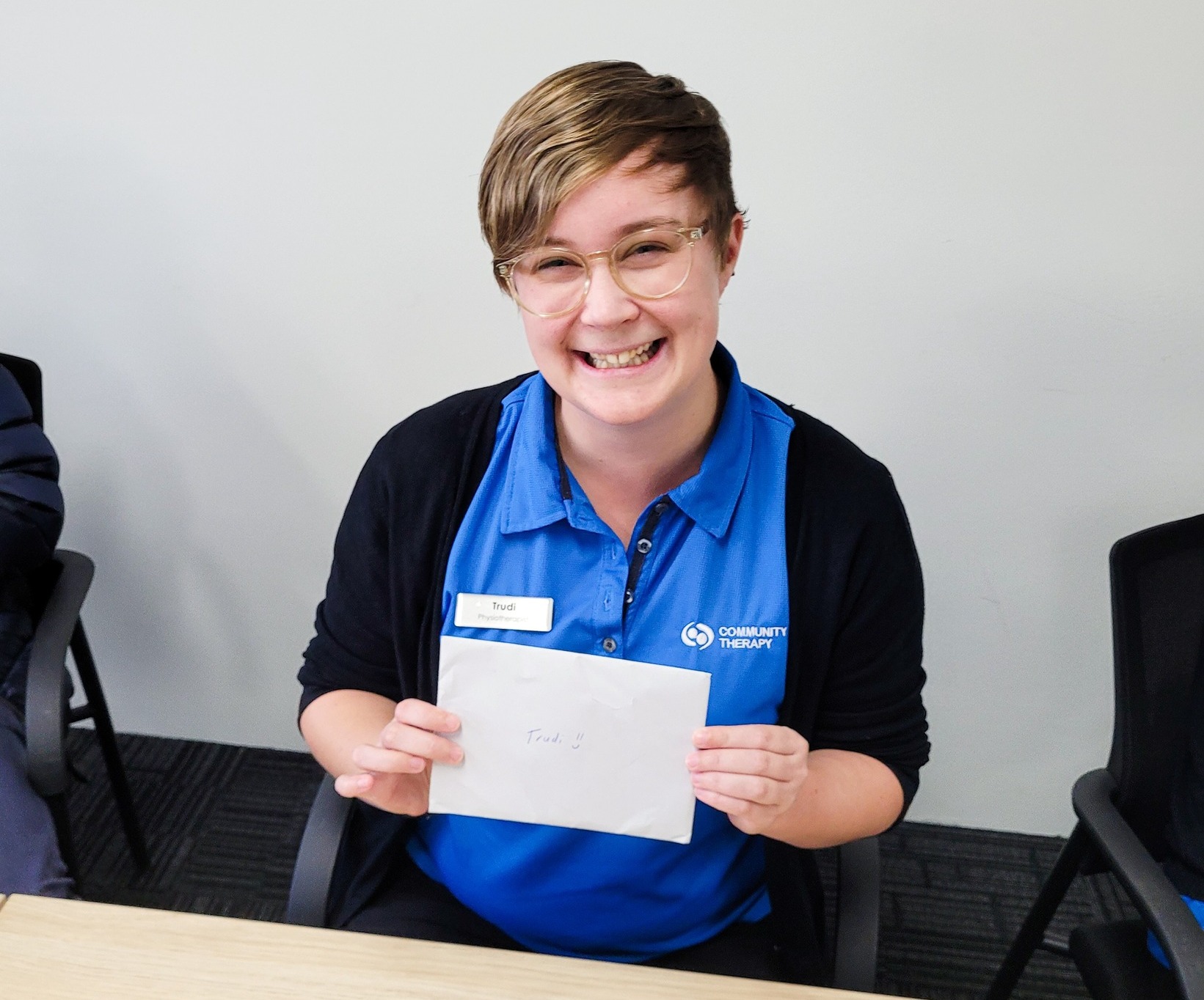 Team member Trudi holding an envelope looking and smiling at the camera