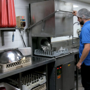 Staff member loading a commercial dishwasher