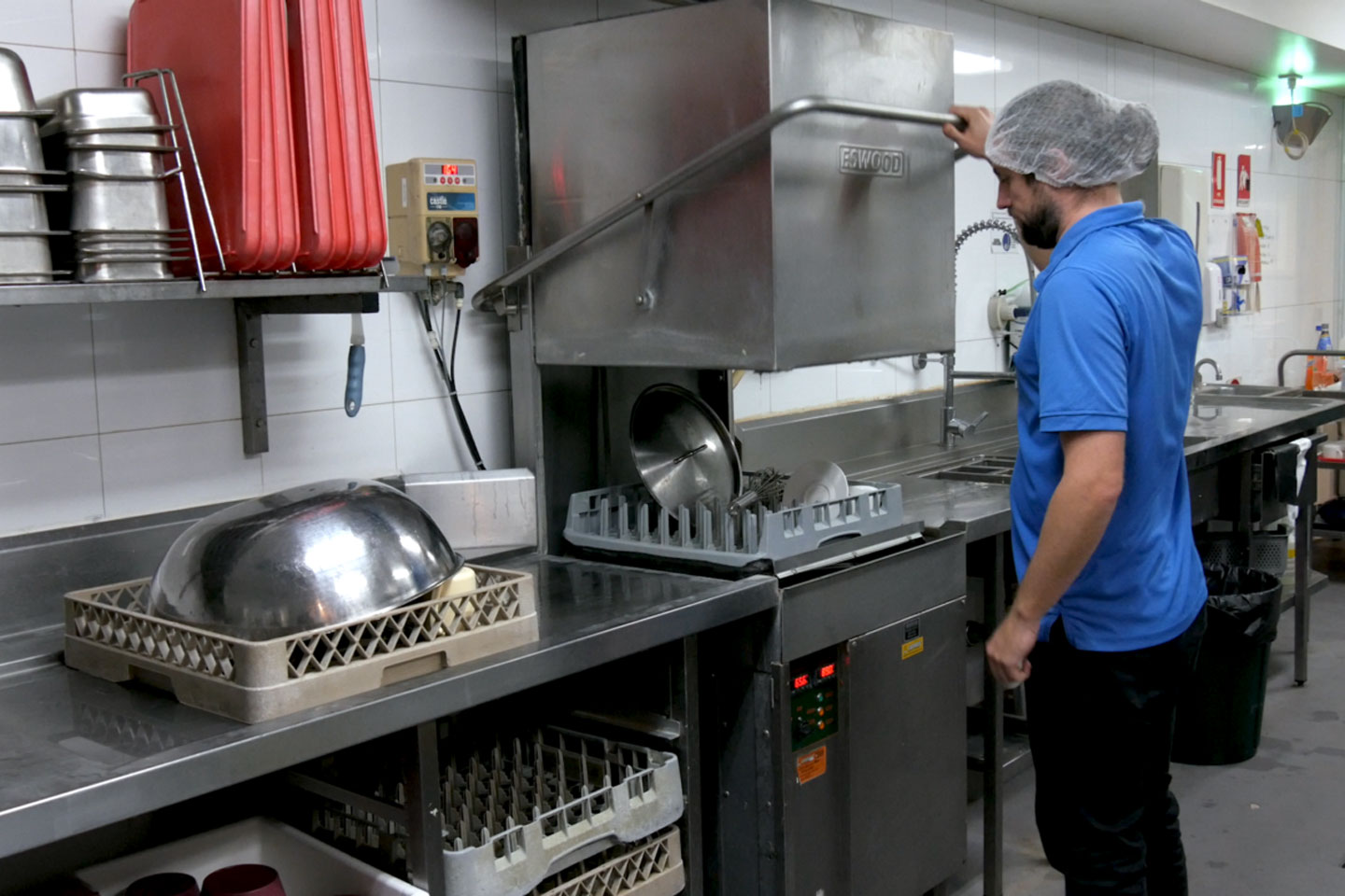 Staff member loading a commercial dishwasher