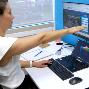 Staff member positioning a computer monitor to achieve a posture positive ergonomics seated work station