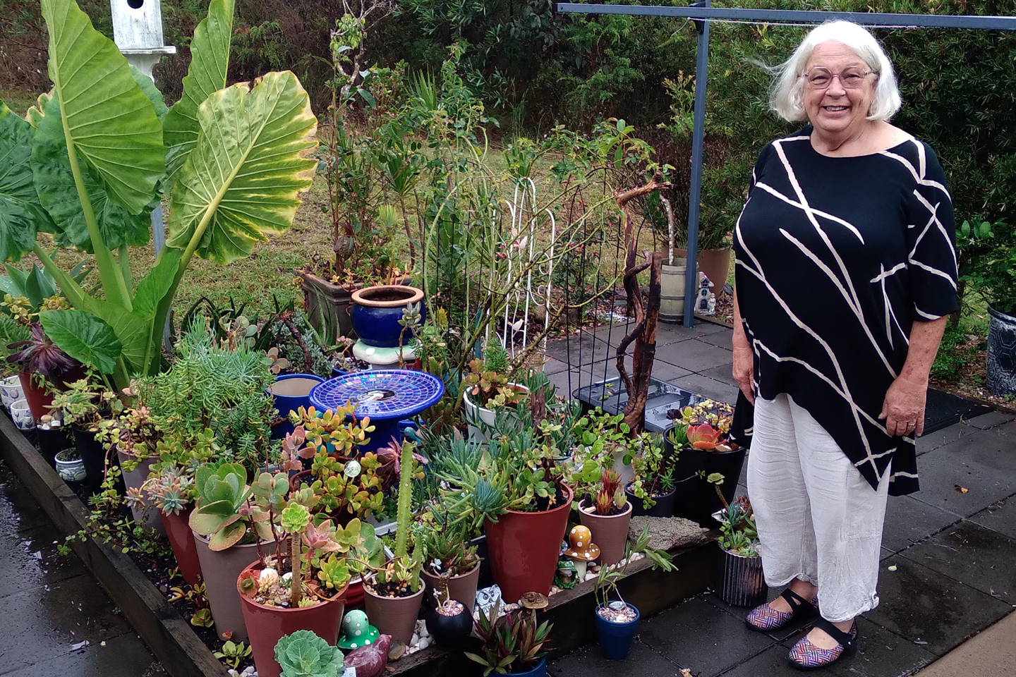 Older adult smiling next to her garden