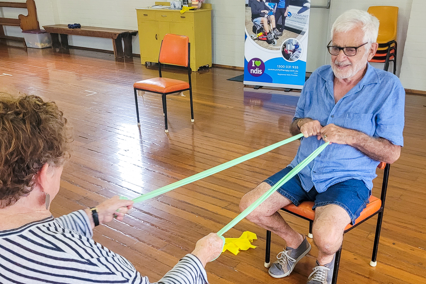 Couple of older adults doing upper body exercises with a theraband