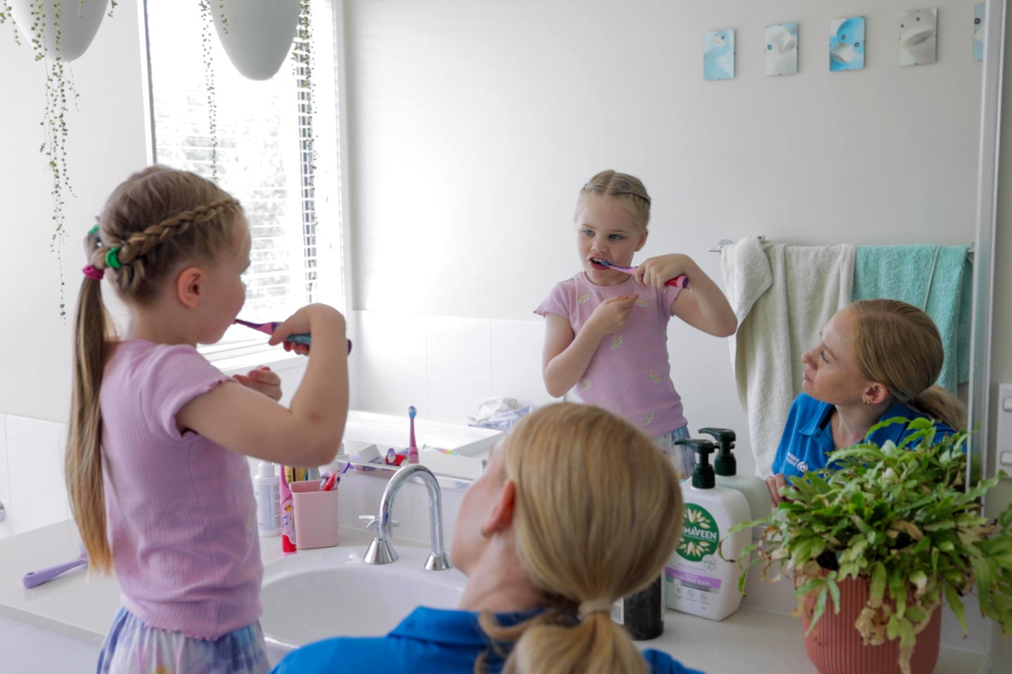 Occupational Therapist and young girl brushing their teeth in the bathroom