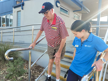 Physiotherapist supporting an NDIS client to navigate stairs