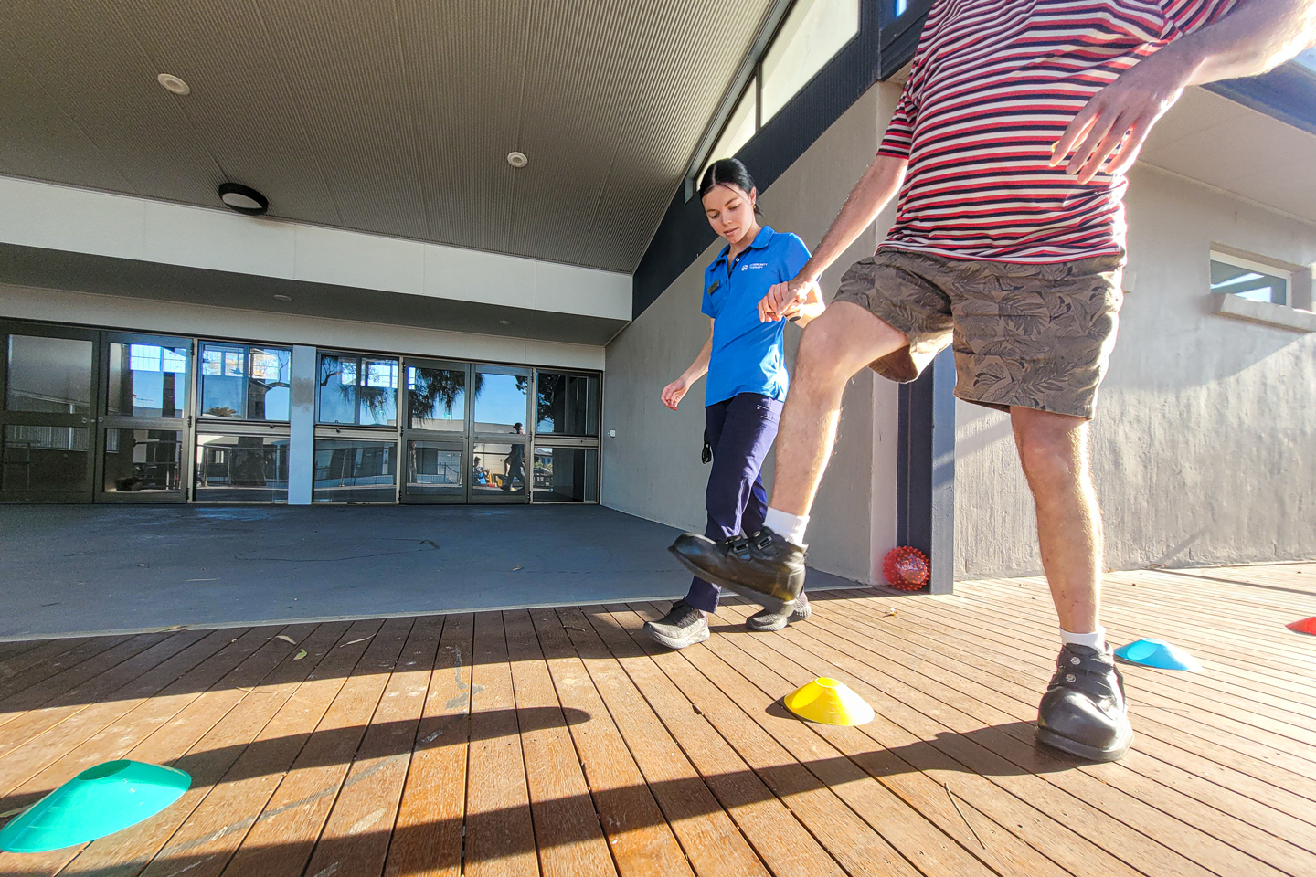 NDIS client and physiotherapist holding hands while doing exercises