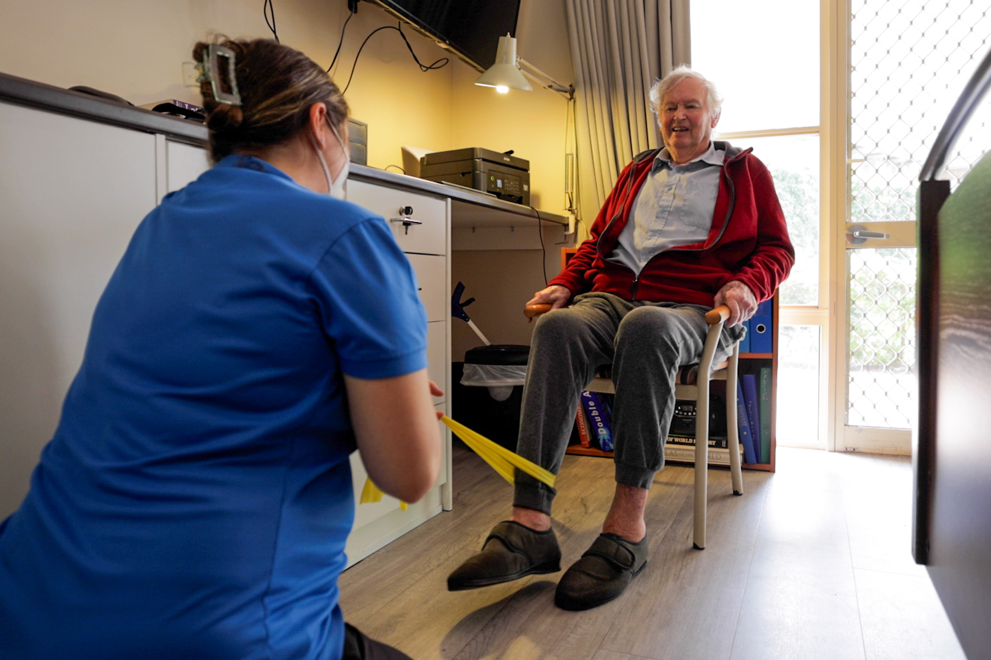 Physiotherapist and older adult doing lower limb resistance exercises