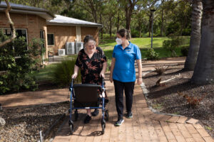Clinician and aged care resident walking outdoors