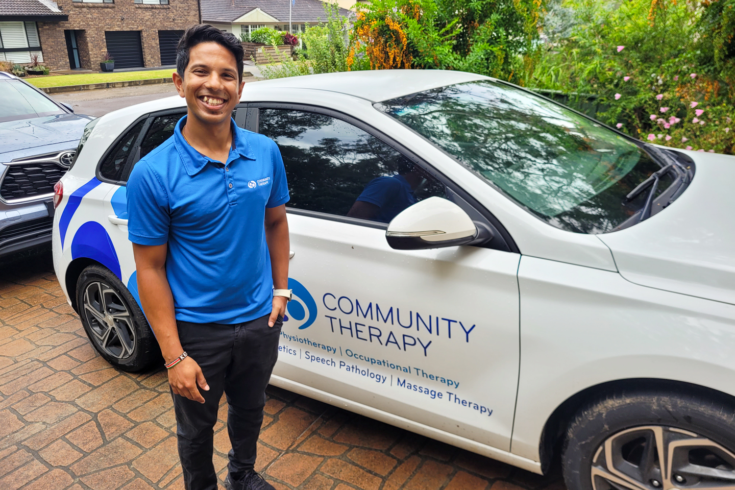 Physiotherapist smiling in front of a branded car